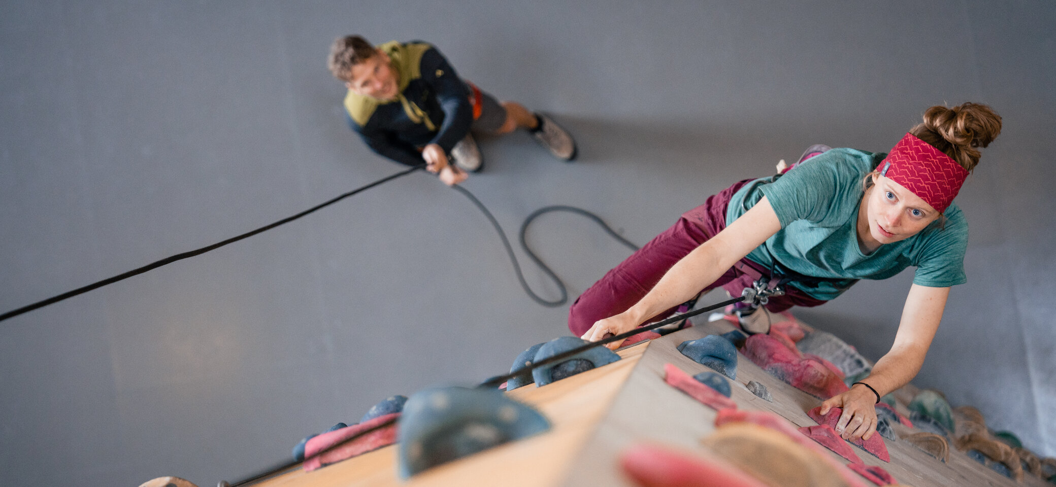 Eine Frau klettert in einer Kletterhalle, ihr Partner sichert sie. | © DAV/Marisa Koch